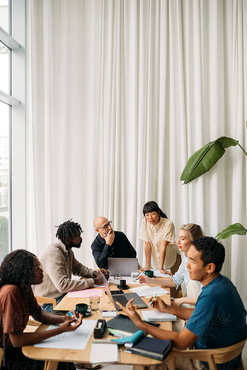Colleagues discussing their work around a table in a bright office